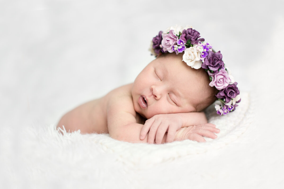 newborn sleeping with wreath of purple flowers on light background, real life, lifestyle,